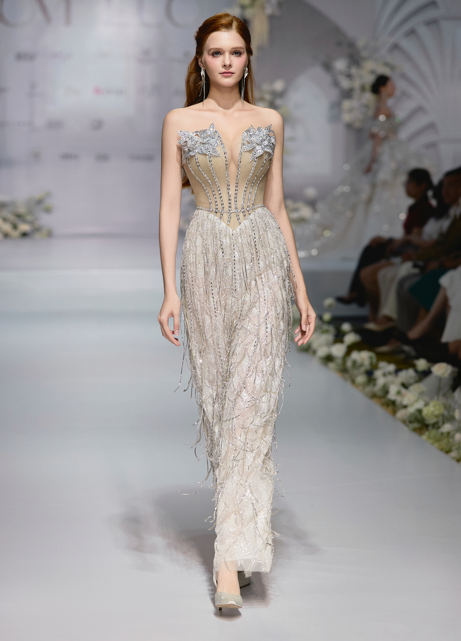 Với xu hướng năm nay, NTK Kim Anh cũng ứng dụng các chi tiết tua rua với những dây đá bạc lấp lánh. Điều này giúp cho những sải bước tăng thêm phần nữ tính, ấn tượng và mang tinh thần phóng khoáng mà bộ sưu tập “Unfolding Her” muốn truyền tải.